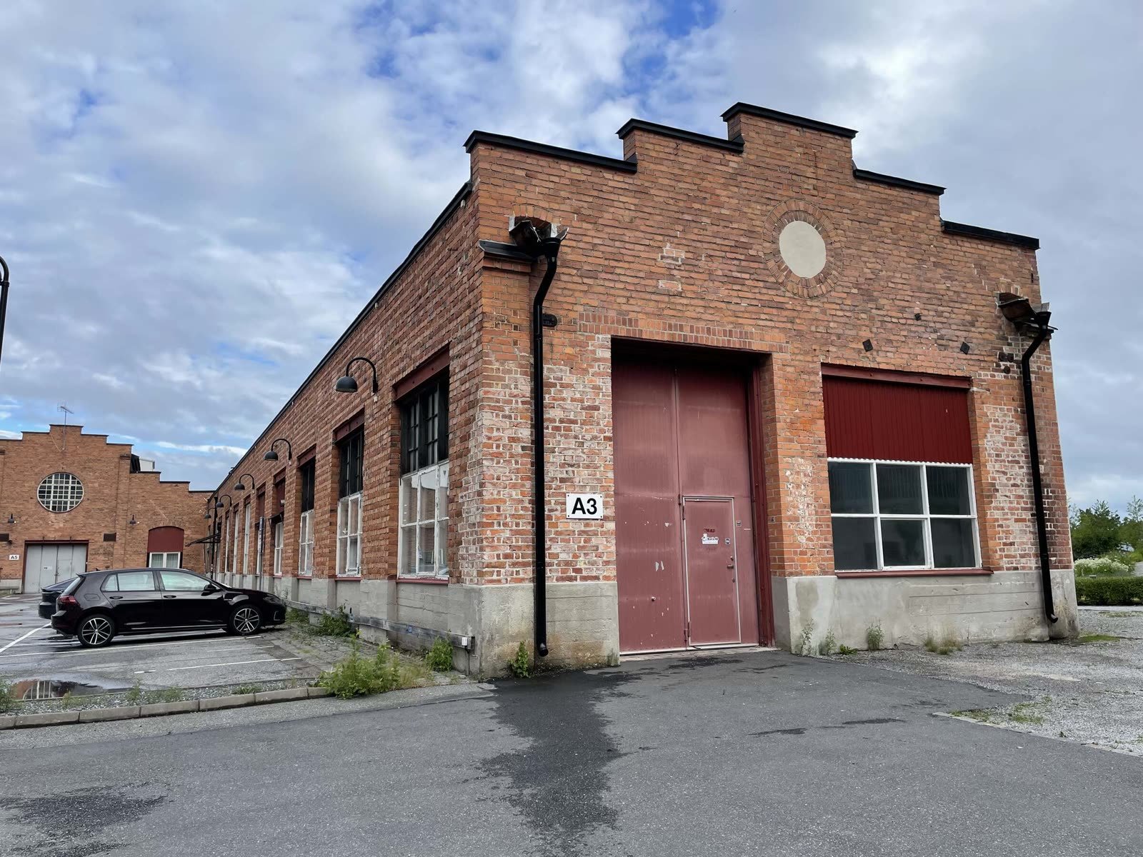 Red-brick industrial workshop building marked "A3" with maroon loading doors under an overcast sky.