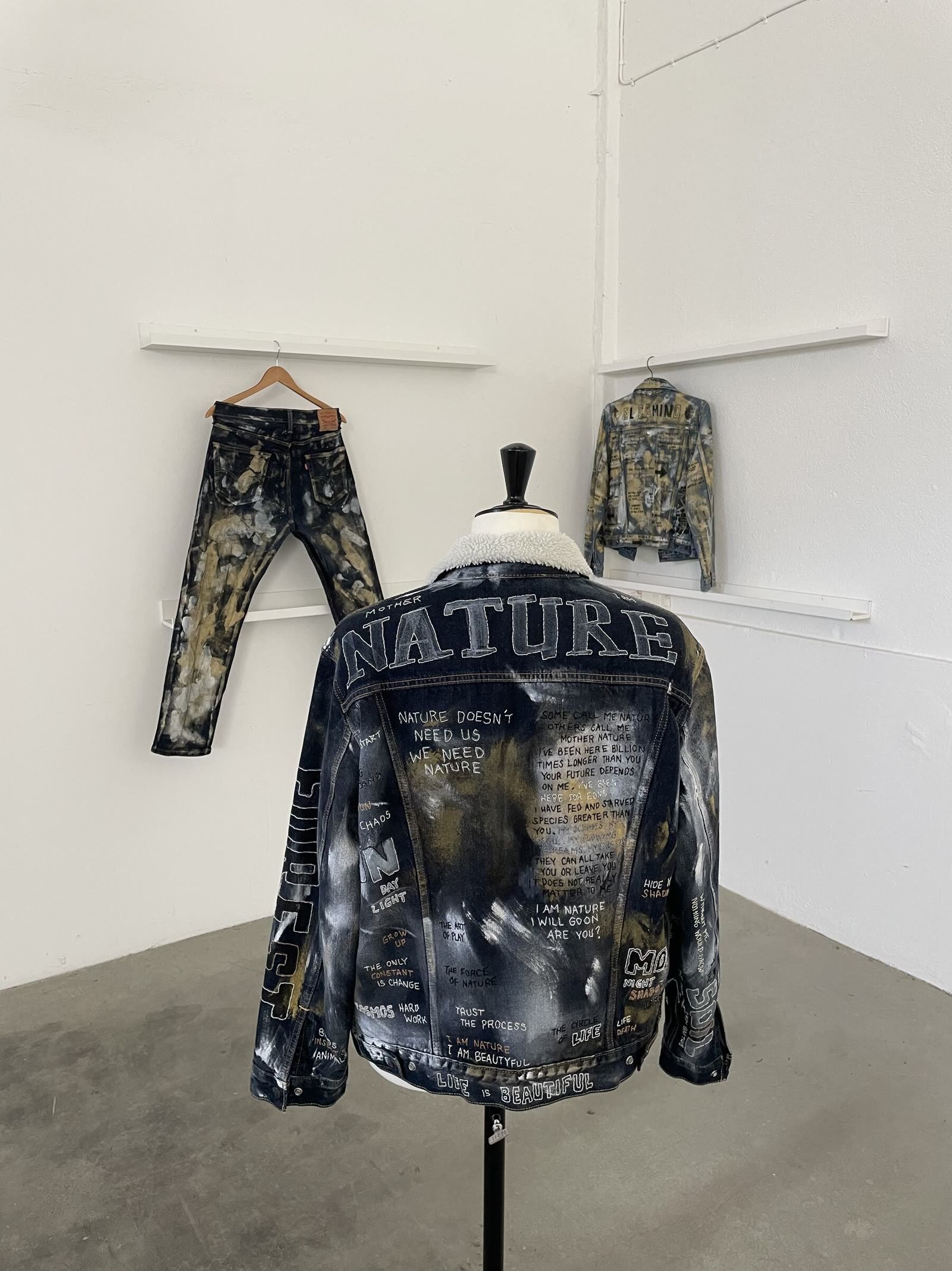 A customized indigo denim jacket and matching jeans on a mannequin, lettered "Mother Nature", in a white studio.