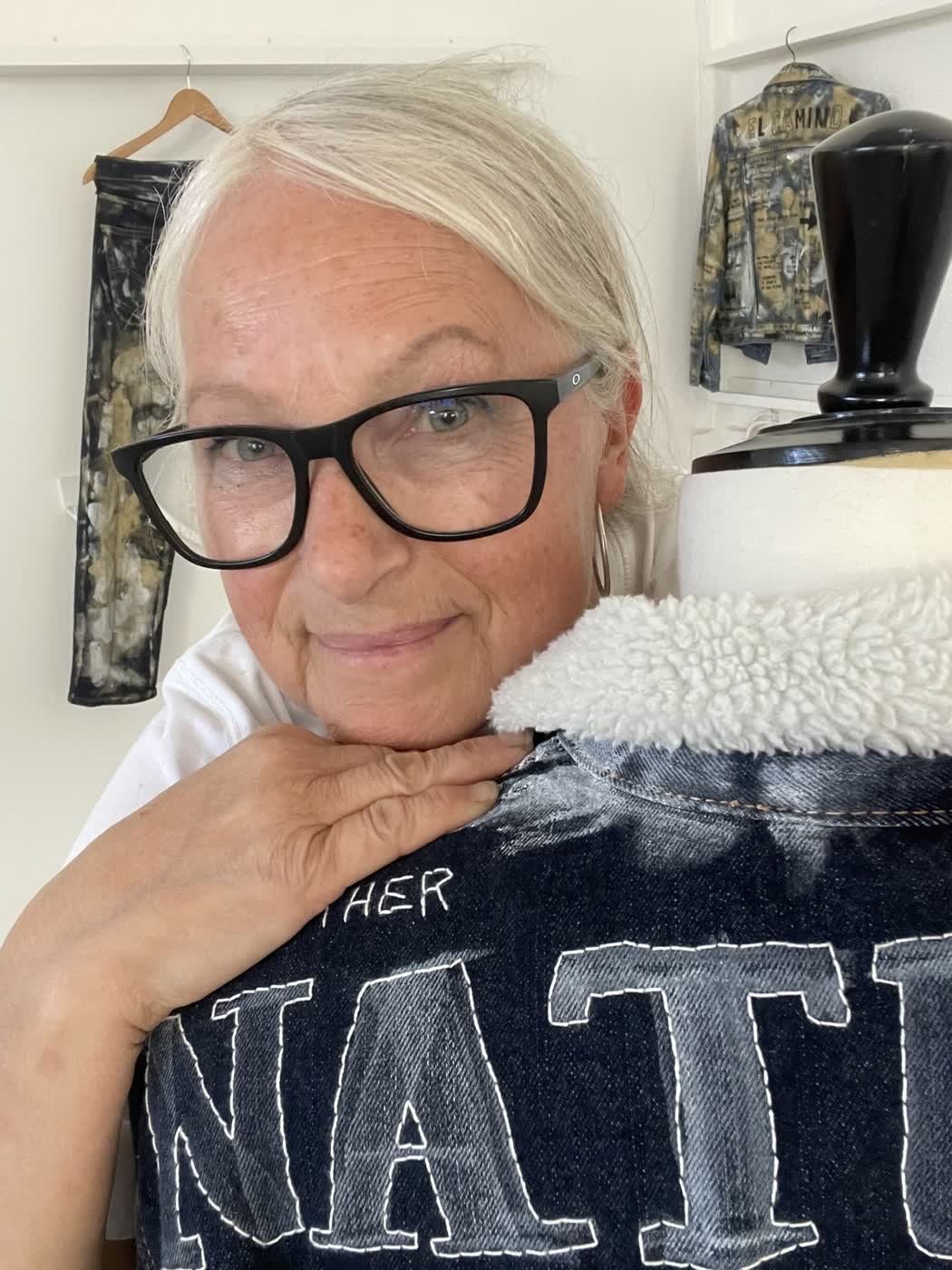 Founder Malin Berglund holds up an indigo sherpa-collar denim jacket with hand-stitched lettering.