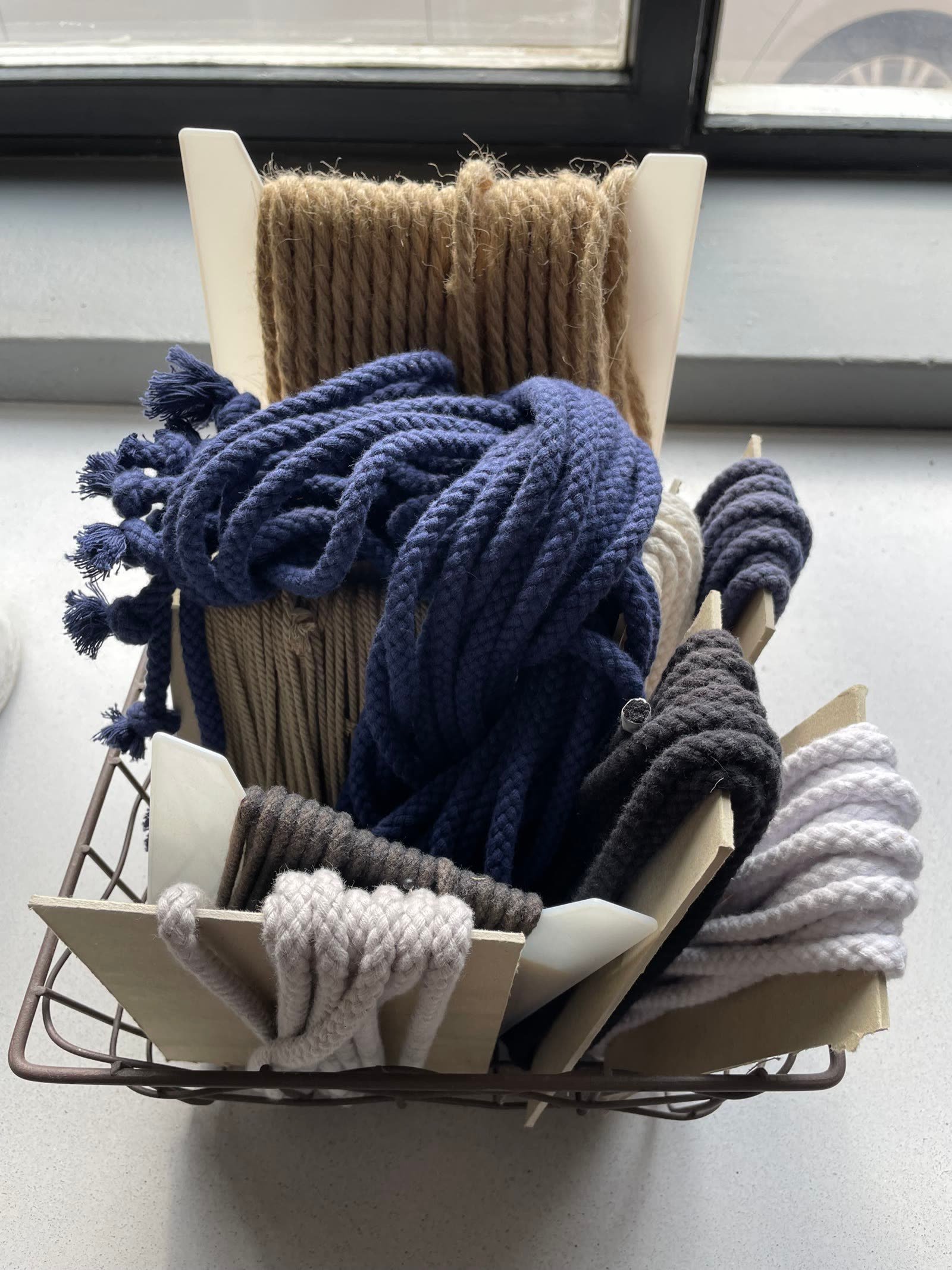 A wire basket of coiled indigo, grey and natural macramé cord and rope.